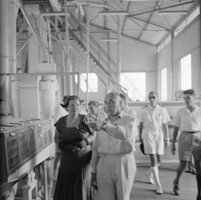Koningin Juliana en prins Bernhard krijgen in 1955 een rondleiding door de rijstfabriek in <div class=